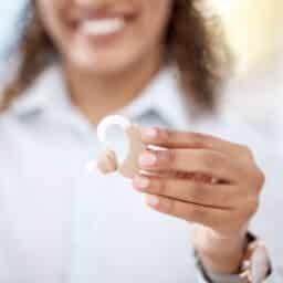 Close up photo of an audiologist holding up a hearing aid