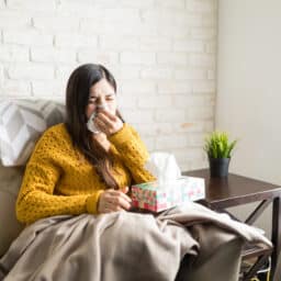 Sick woman blowing her nose in a tissue at home
