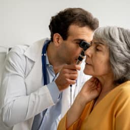 Doctor examining his patient's ear with an otoscope.