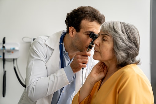 Doctor examining his patient's ear with an otoscope.
