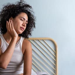 Woman with an ear infection holding the affected ear.