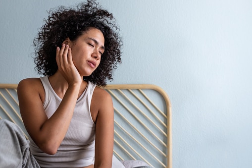 Woman with an ear infection holding the affected ear.
