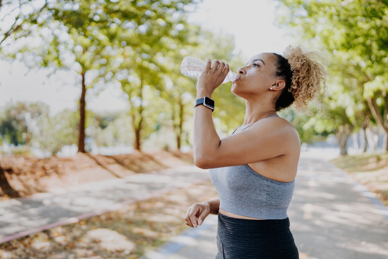 Fitness runner woman drinking water.
