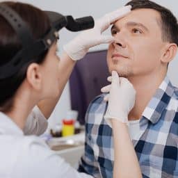 ENT specialist examining a man's nose.